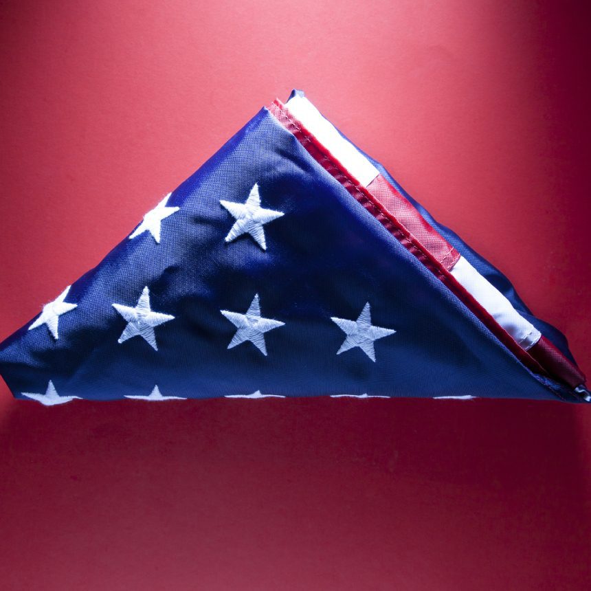 Folded American flag on red background.